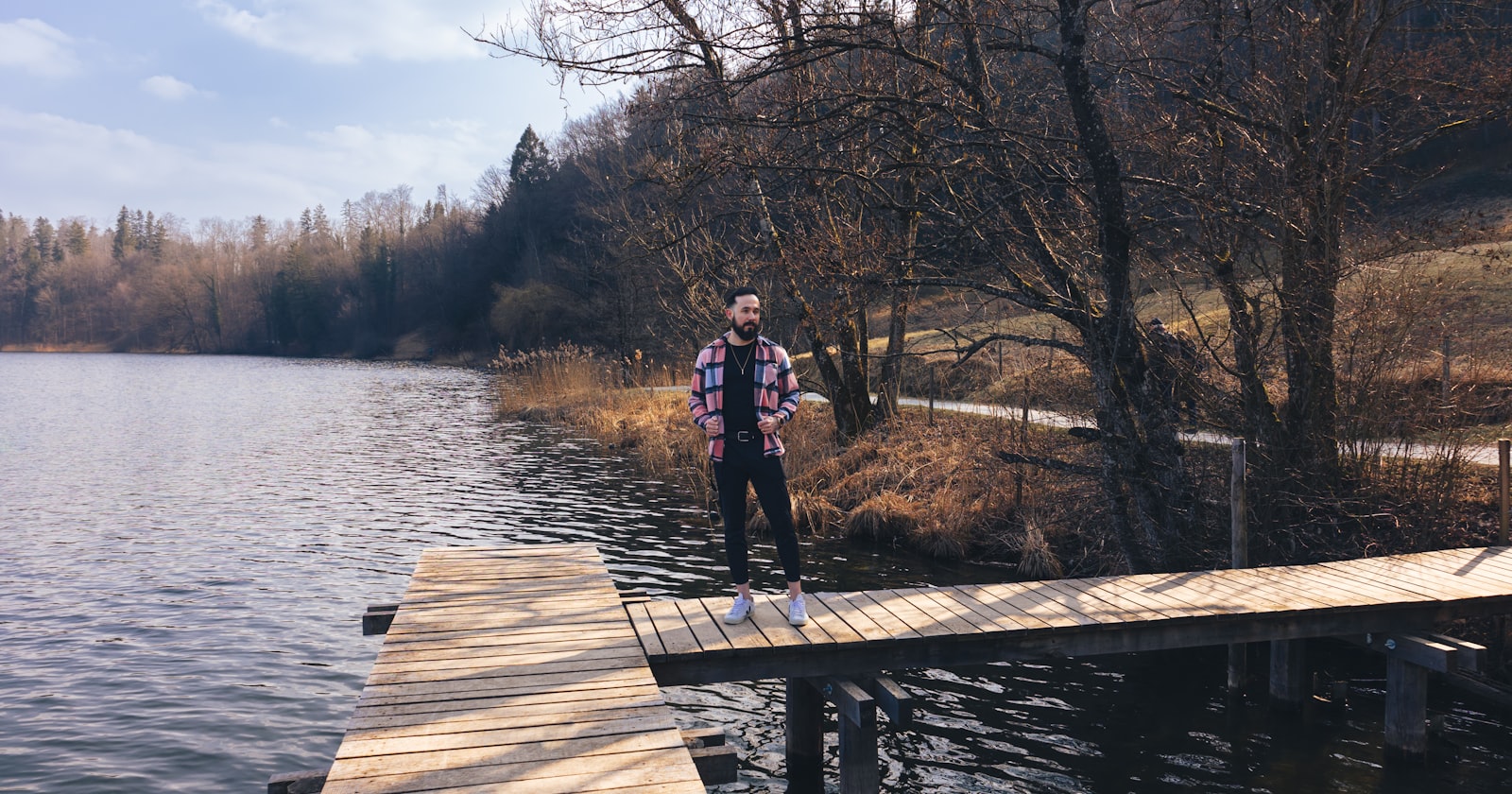 a man standing on a dock next to a body of water