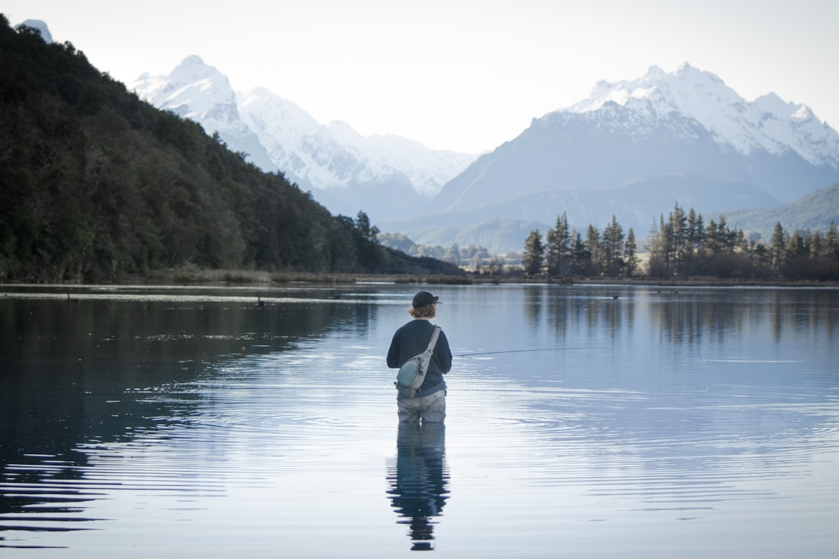 a man standing in the water holding a fish